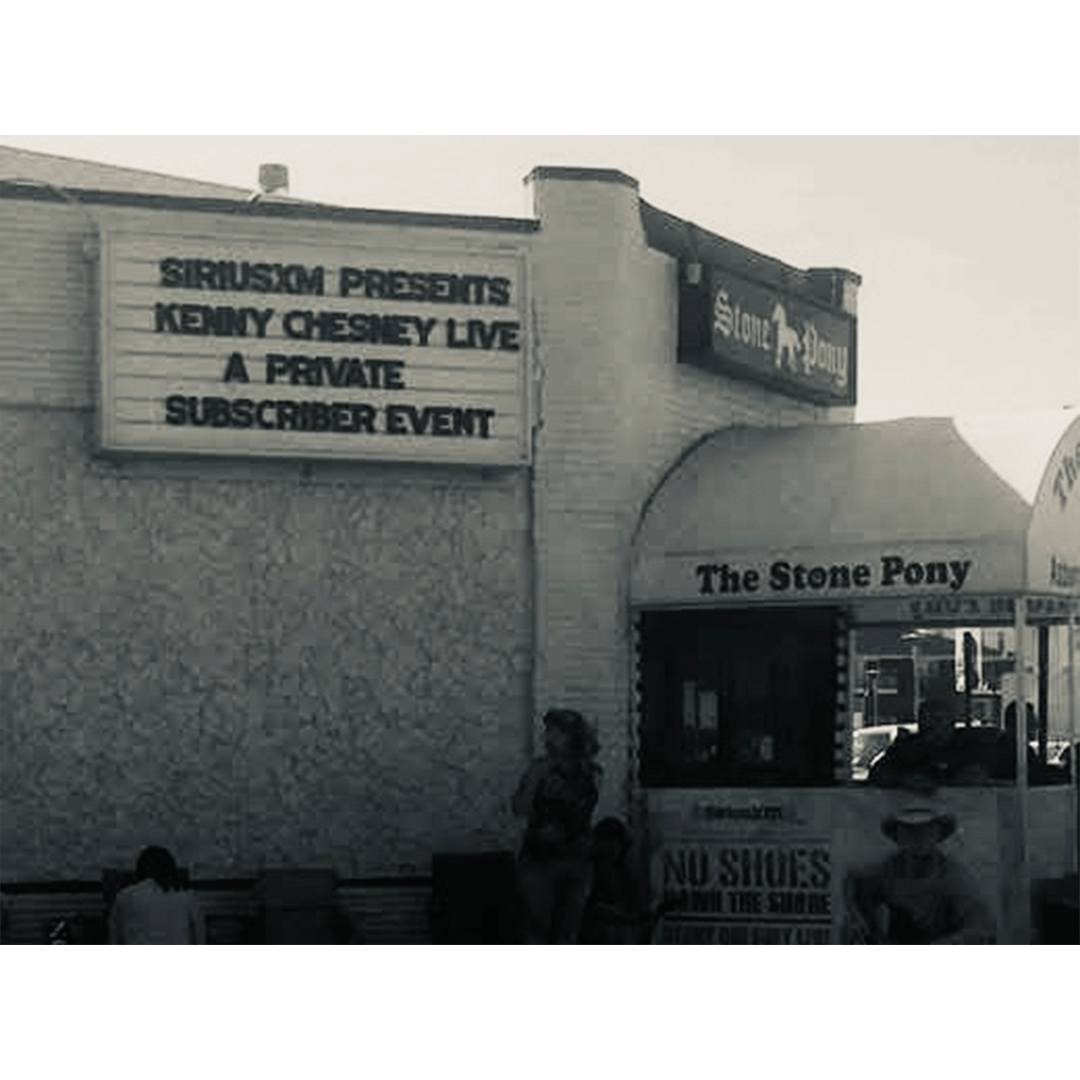 The image shows The Stone Pony venue with a marquee sign reading "SiriusXM Presents Kenny Chesney Live, A Private Subscriber Event." The tone is nostalgic.