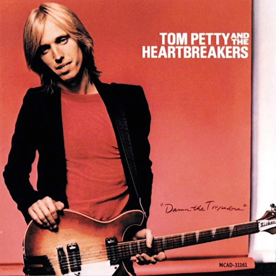 Album cover of "Damn the Torpedoes" by Tom Petty and the Heartbreakers. Features a person with long hair holding a guitar against a red background.