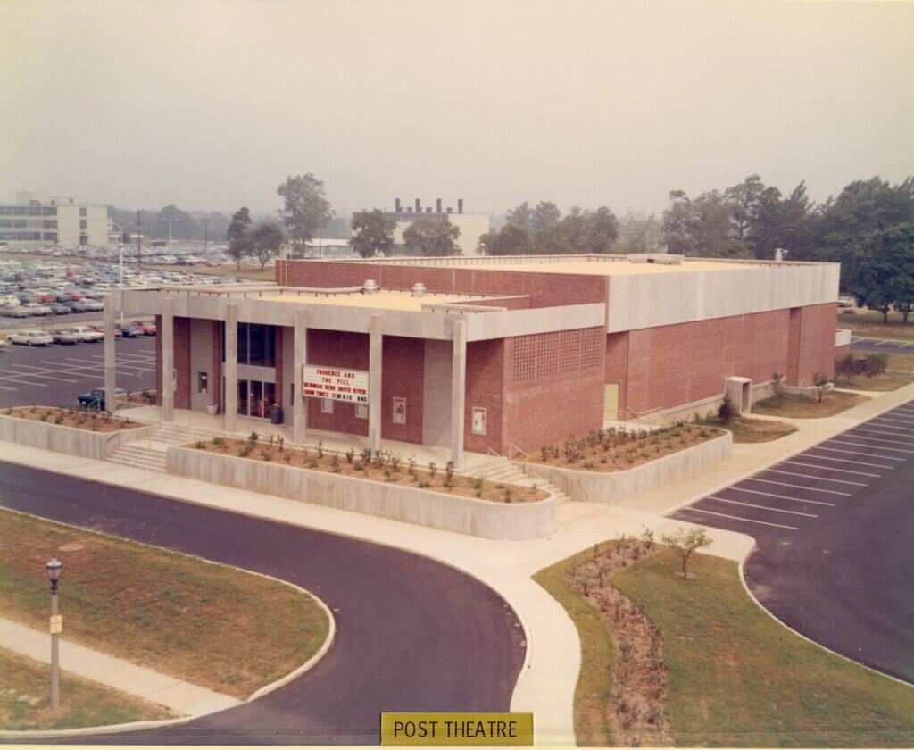 Aerial view of a large brick building labeled "Post Theatre" with marquee, surrounded by empty parking spaces, trees, and a distant parking lot.
